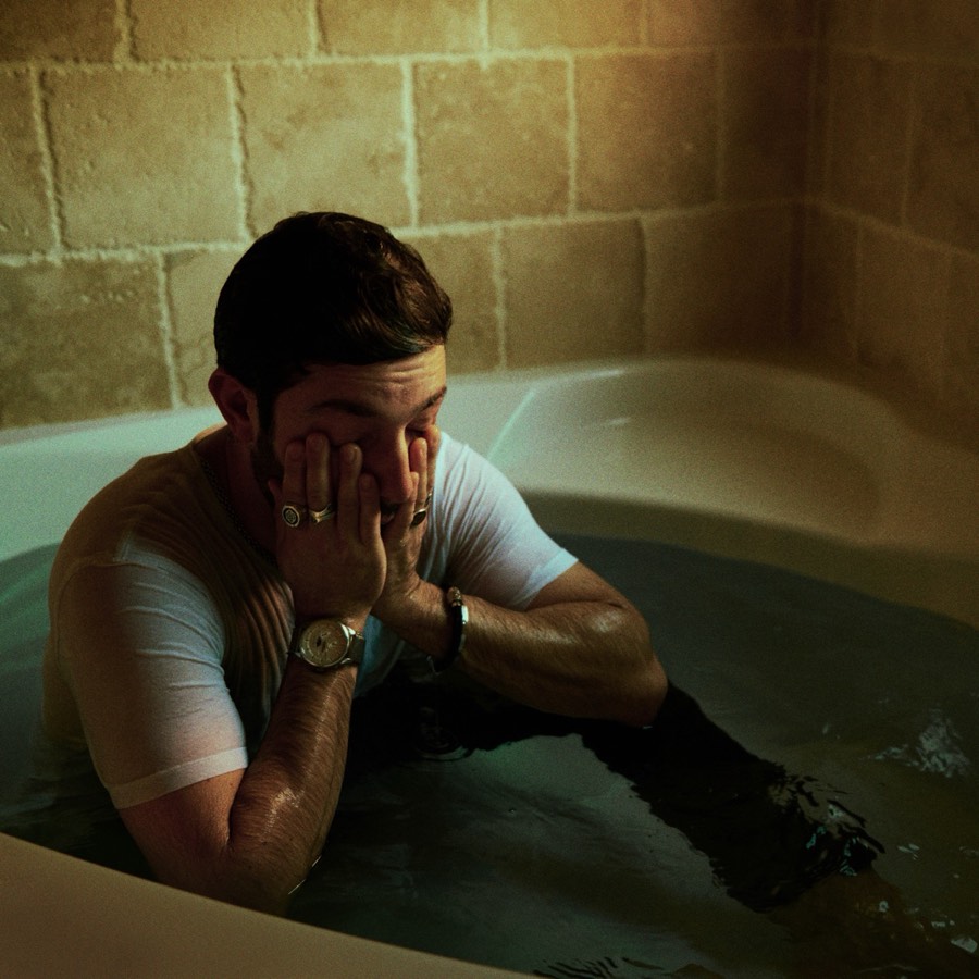 babylon cover: Sam Haiman sitting in a bathtub in a cinderblock room